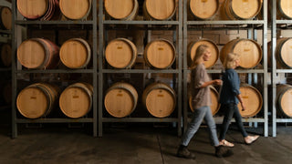 Mother-daughter winemakers Kate & Penelope Radburnd walking past French oak barrels in Radburnd Cellars cellar, Hawke's Bay.