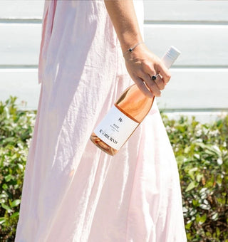 Penelope Radburnd walking along holding a bottle of Radburnd Cellars Penelope Rose, Hawke's Bay